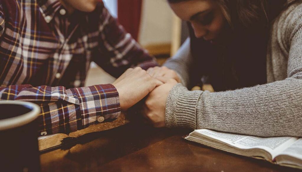 Closeup of a couple holding hands on the table with a blurry background