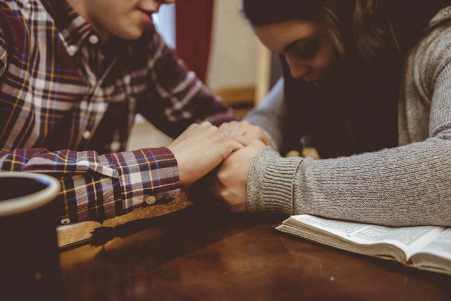 Closeup of a couple holding hands on the table with a blurry background